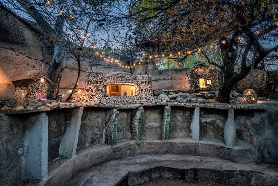 a photograph of a home's exterior with numerous forms and passageways created from pebbles and concrete