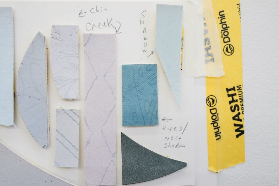 pieces of canvas and yellow tape pasted on a surface with notes about the placement on a painting, like 