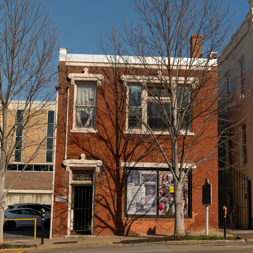 Exterior brick building with large tree in foreground.