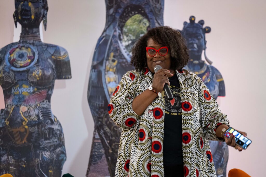 Person with microphone in hand is flanked by statues.