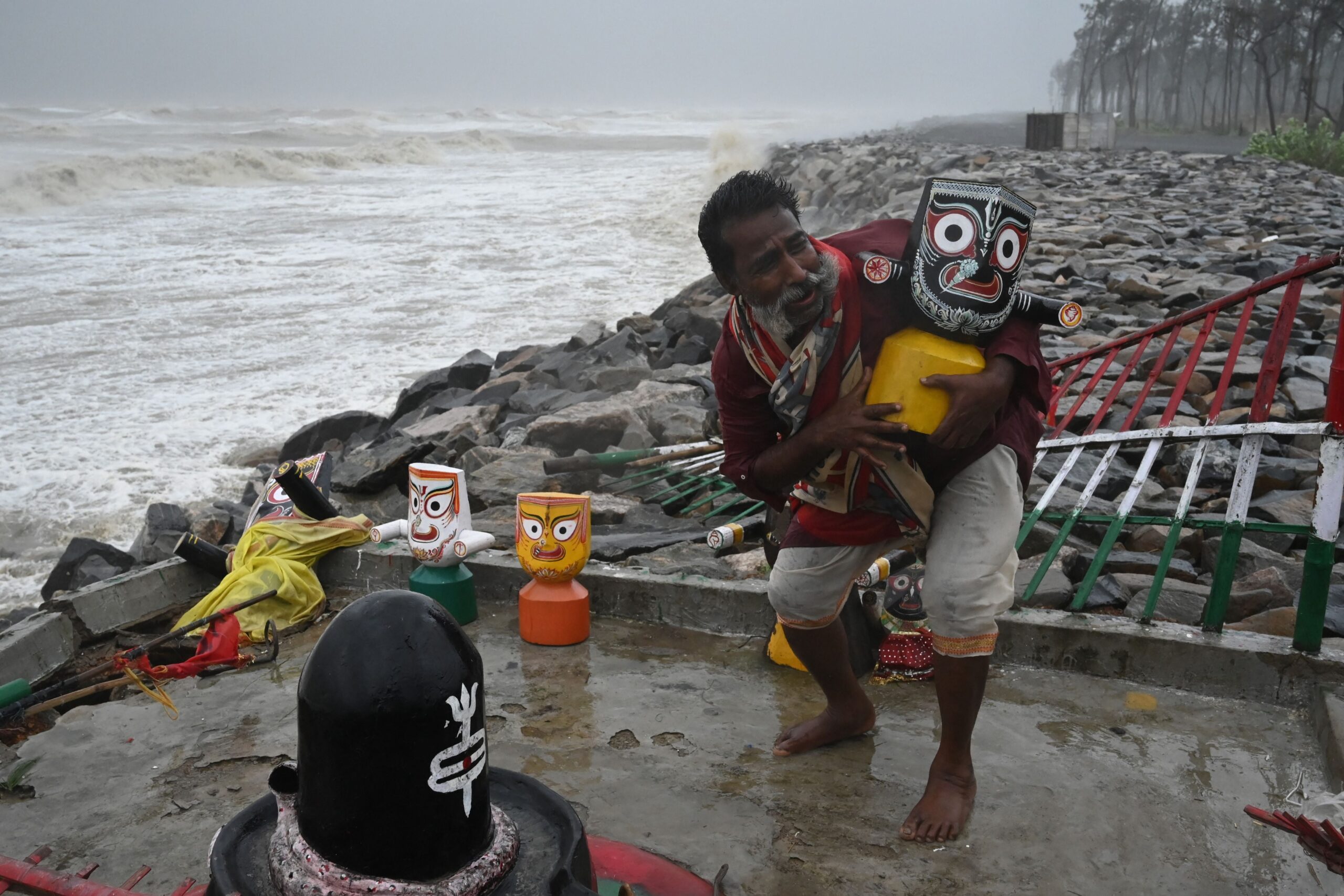 A Hindu priest removes an idol of Lord Jagannath from a seafront temple to a safer place while strong winds batter Balasore district in Odisha state on May 26, 2021 as Cyclone Yaas barrels towards India's eastern coast in the Bay of Bengal
