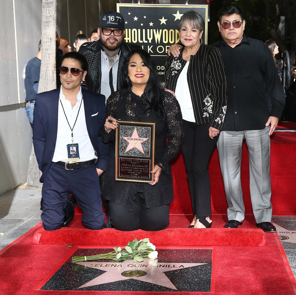 chris perez, ab quintanilla iii, suzette quintanilla, marcella samora, and abraham quintanilla jr pose for a photo as they kneel and stand behind a star bearing selena quintanillas name