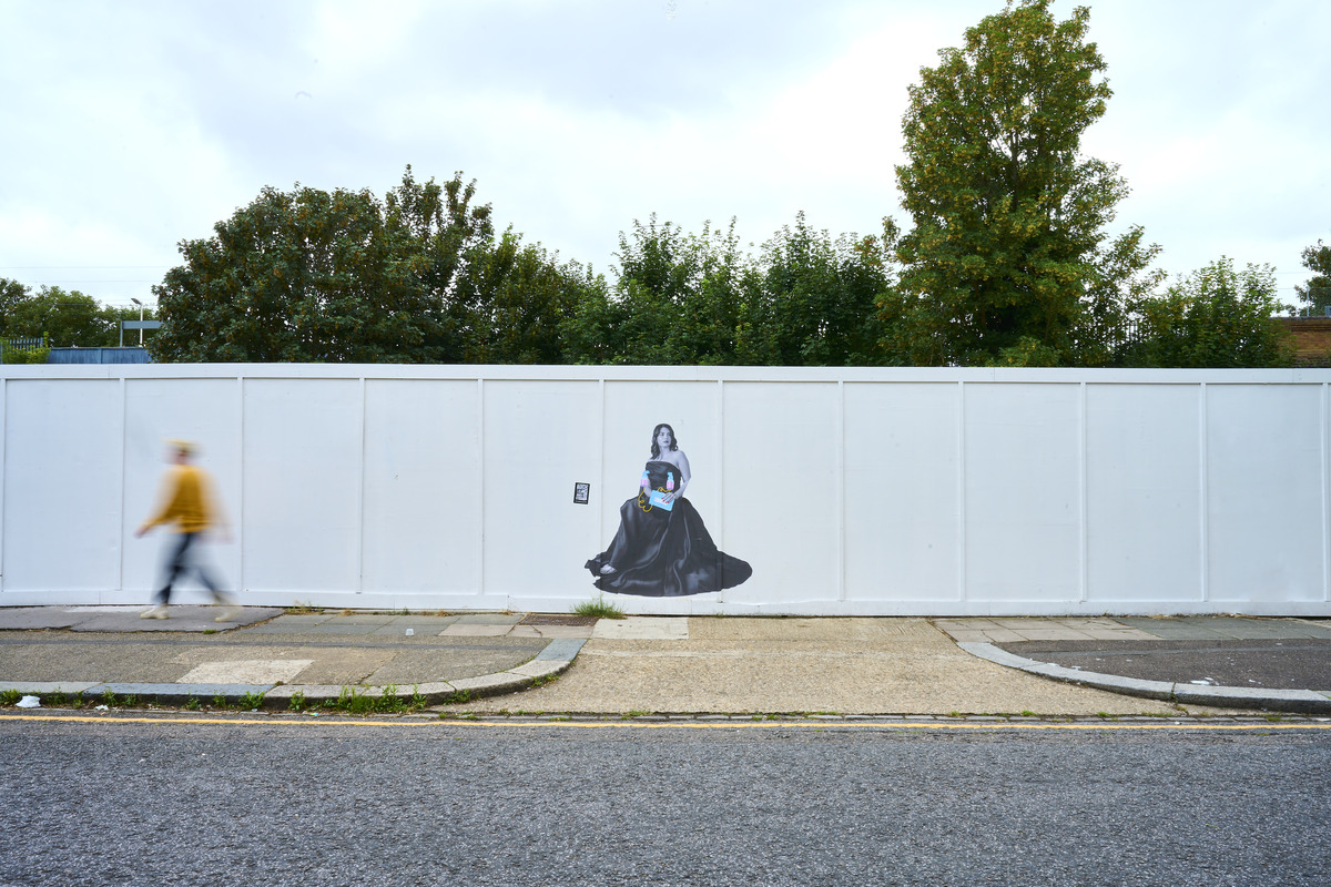 Person walking past a street art mural of woman in dress.