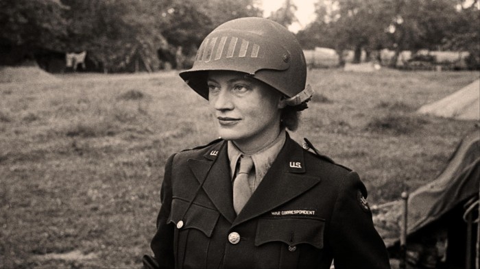 A black and white photo of a woman wearing a military uniform and helmet on her head