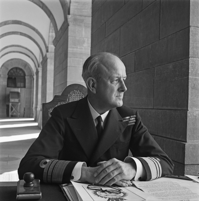 A black and white of a man in uniform sitting at a desk