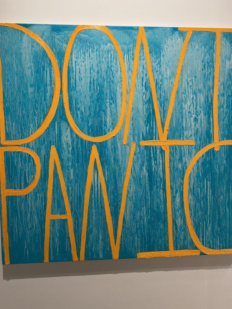 an image of bright yellow letters on a blue background spelling out the words Don't Panic