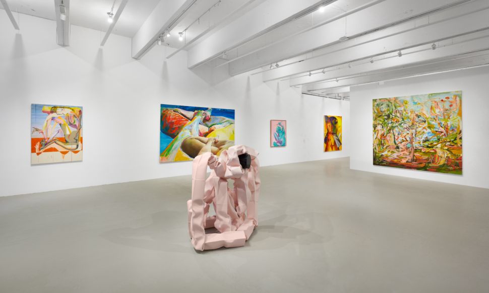 A brightly lit interior of an art gallery with several artworks displayed on the walls and in the center of the room