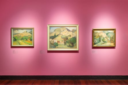 Three gold and green landscape paintings hung on a pink wall