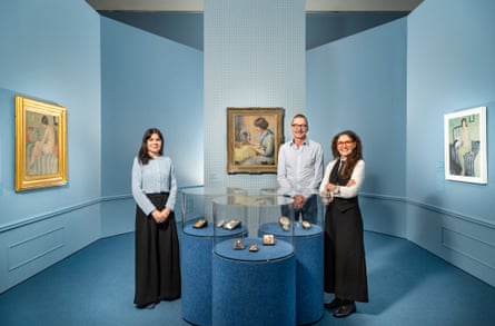 Three curators stand in a gallery with blue walls