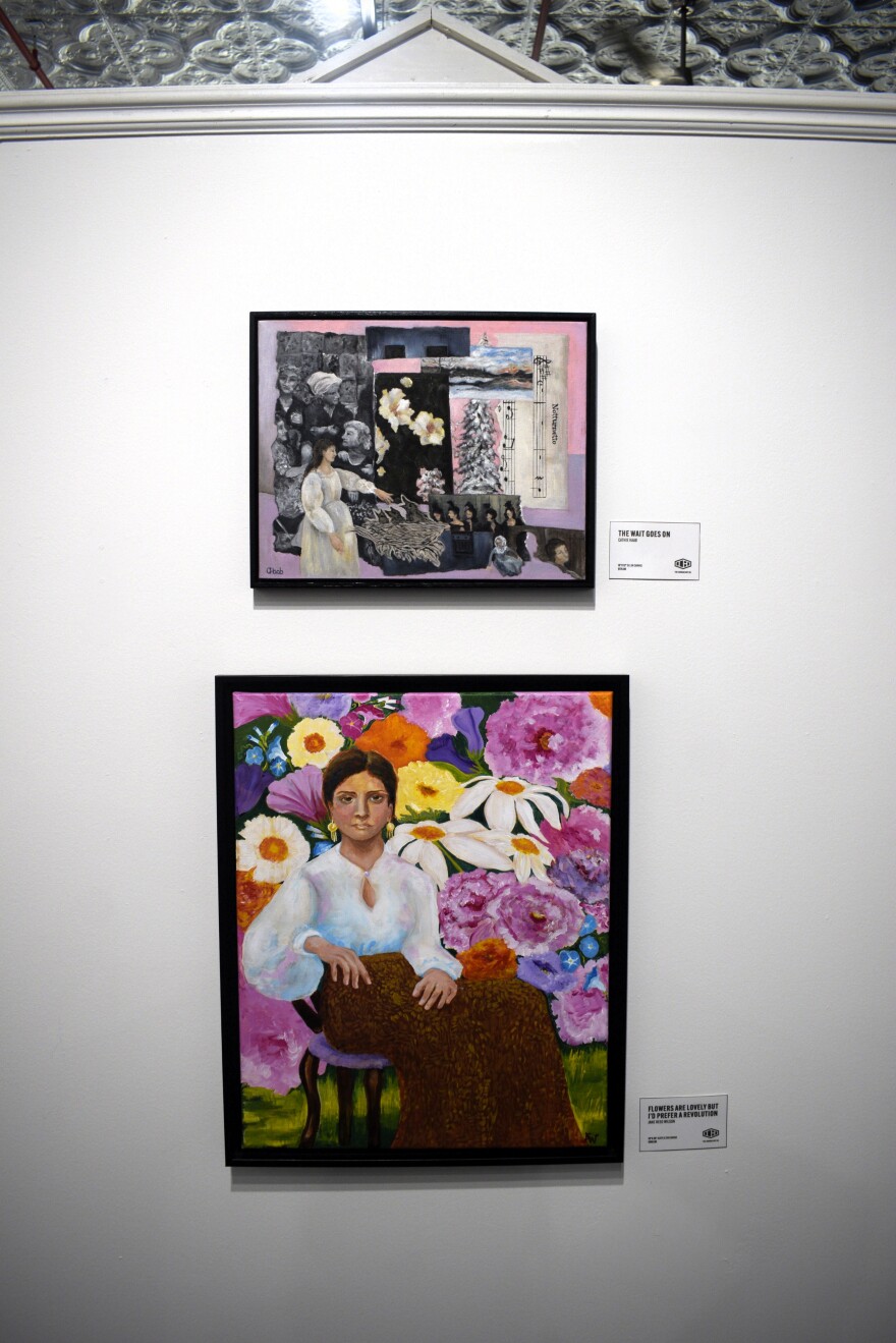 Two framed artworks hang on a white gallery wall. The top piece is a collage with black-and-white photos and floral elements, while the lower piece is a colorful painting of a woman seated among large vibrant flowers.