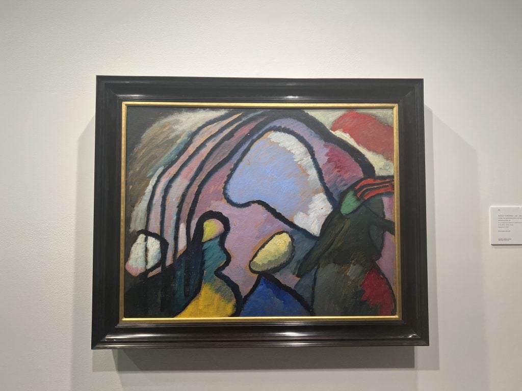 An abstract painting with bold, sweeping black lines framing colorful, fluid shapes in blue, yellow, red, and green tones, all set against a muted background.