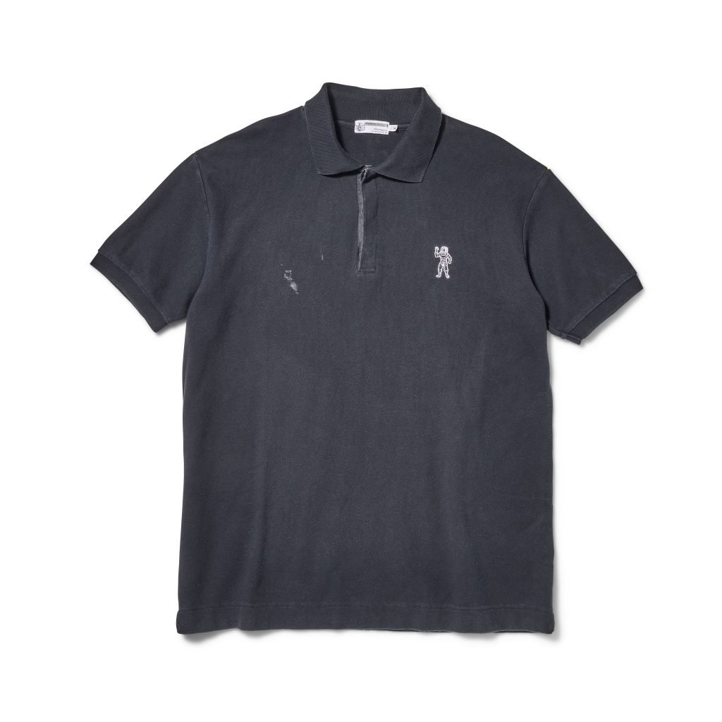 Faded black polo shirt with astronaut logo patch and subtle wear marks on chest.