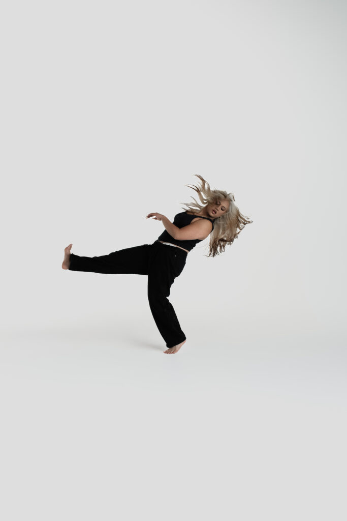 A dancer kicking her foot out flexed with her hair flying out.