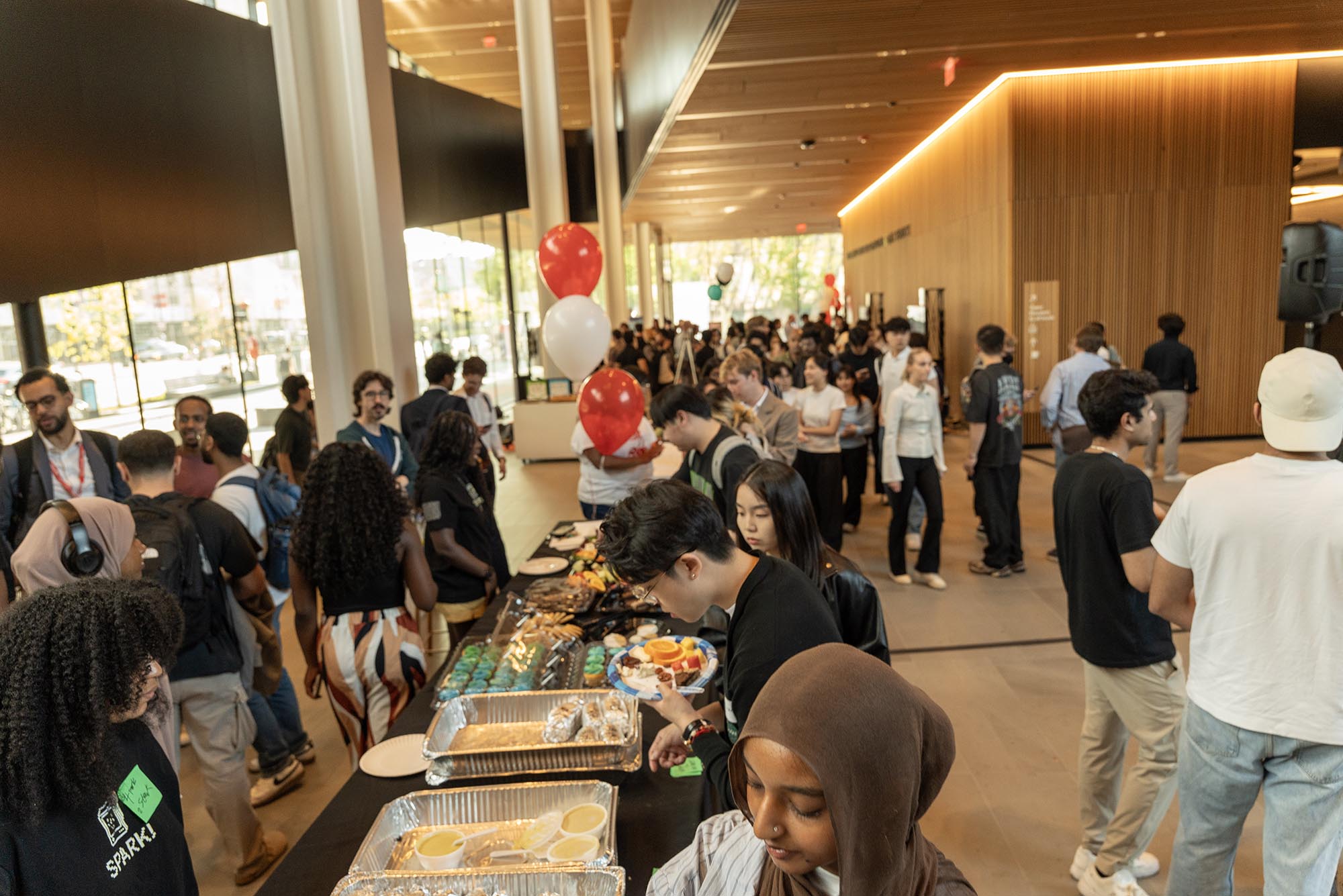 Photo: A crowd mingling with a large, long table full of food.