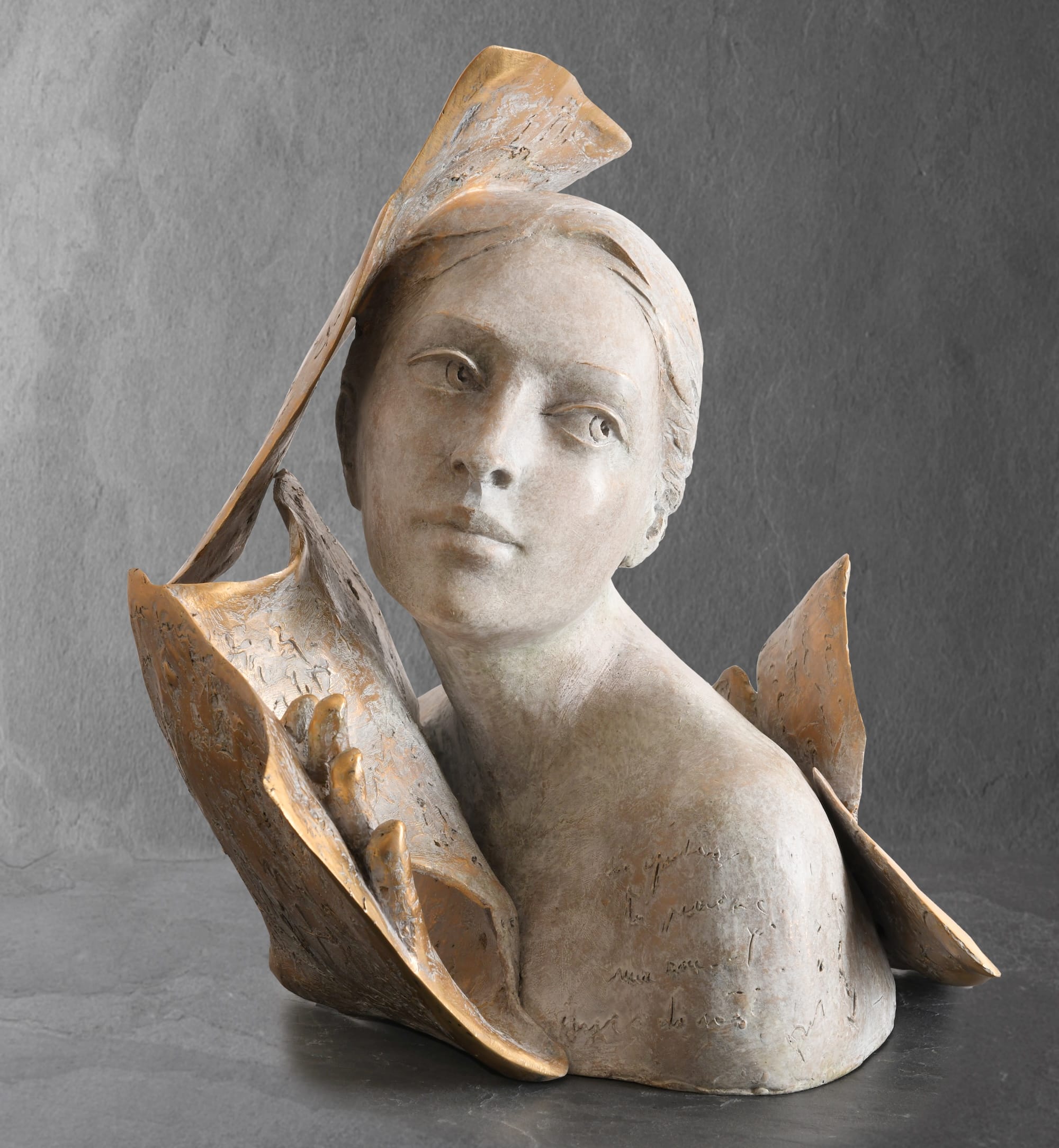 a sculpture of a woman's head and shoulders, surrounded by book or manuscript pages