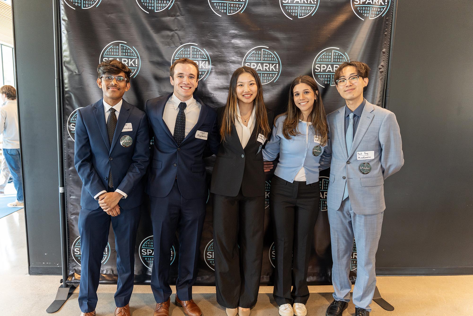 Photo: A group of students in formal attire pose in front of a black back drop.