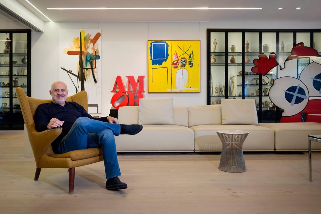 Nazem Ahmad, art collector, sitting in a chair in his art-filled home.
