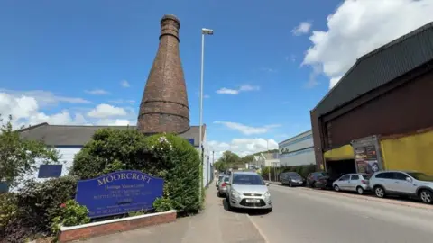 A street next to a pottery. A blue sign on the left says