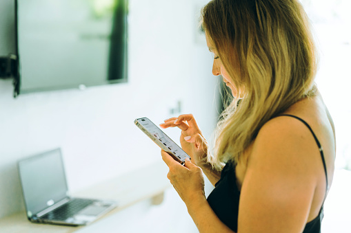 Woman in the hotel room with mobile phone