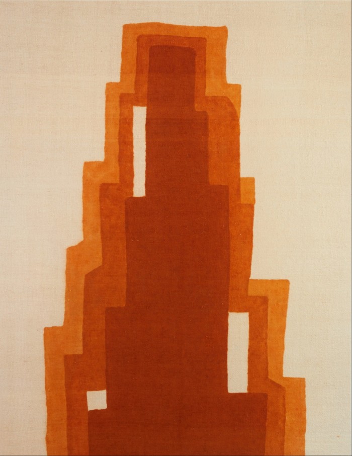 Woven fabric piece of art, in a portrait format, where a jagged triangle in various warm shades of orange lies on a white background