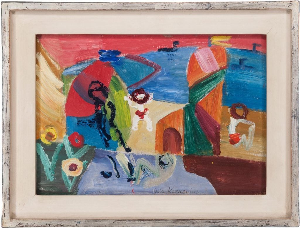 A colorful abstract painting by Ida Kerkovius titled Urlaub am Meer (Holiday by the Sea), created around 1950. The composition features vibrant brushstrokes in red, blue, green, yellow, and earthy tones, suggesting a seaside landscape with stylized human figures. In the foreground, loosely rendered figures lounge or play, surrounded by geometric shapes and bold color fields that evoke flowers, umbrellas, and architectural forms. The sea is depicted in deep blue tones under a pink-red sky. The painting is set in a distressed white wooden frame, emphasizing its modernist charm and playful energy.