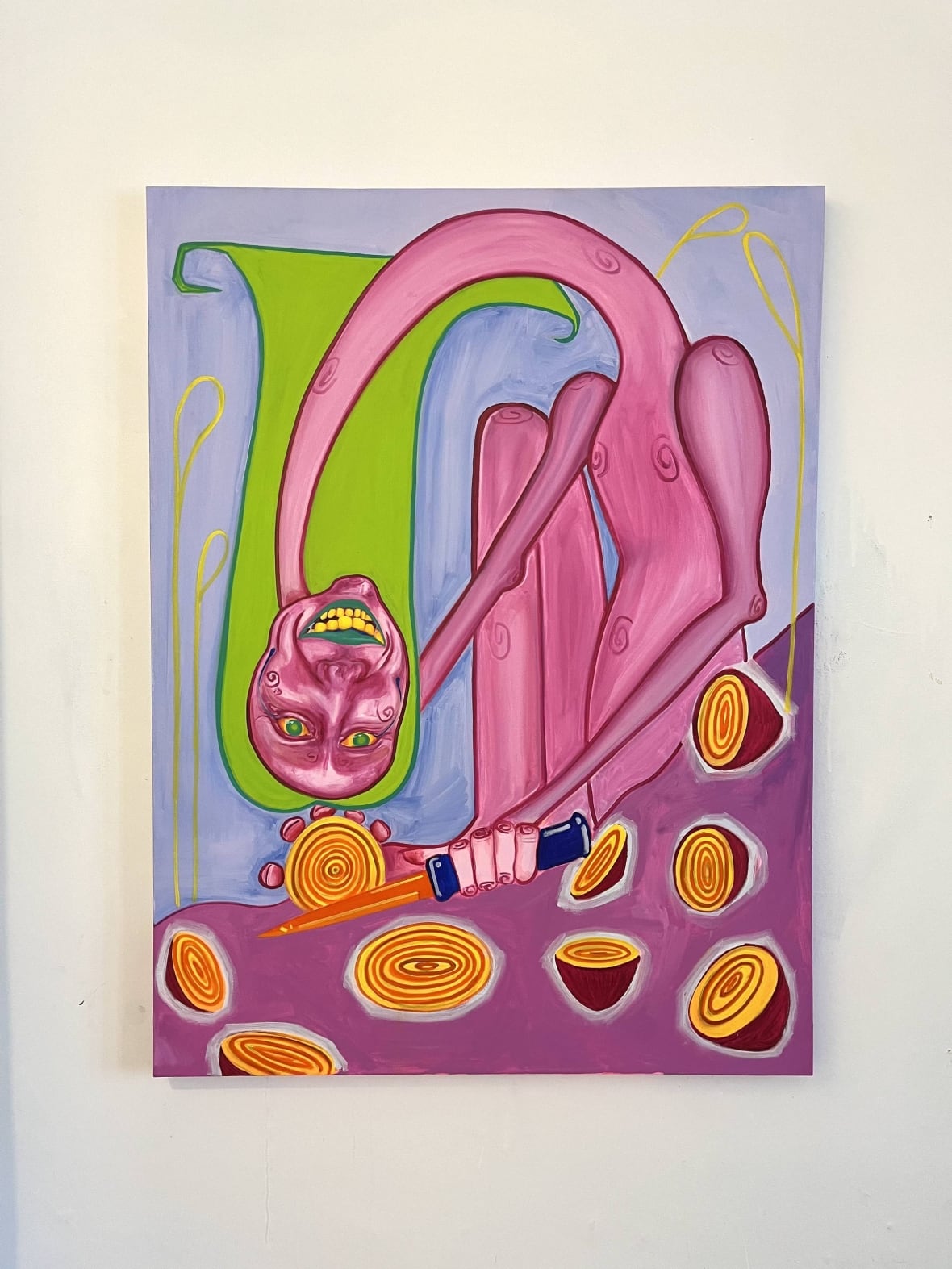 Painting in a 2D surreal style. A pink, nude female figure crouches in front of a mauve surface covered with chopped yellow and purple onions. She holds an orange blade and slices an onion in half. Her neck is comically long and bendy, and droops toward the counter. It is smiling broadly to display yellow teet and green and yellow eyes. Her hair is long and lime green.